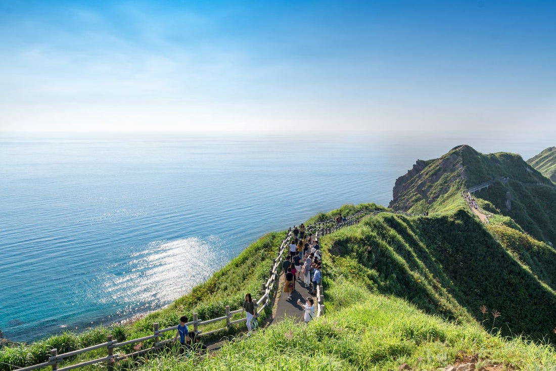 people walking a mountain trail next to the water