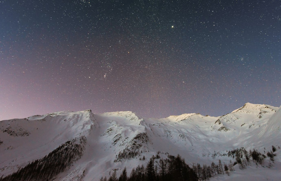 snowy mountains in front of starry night sky