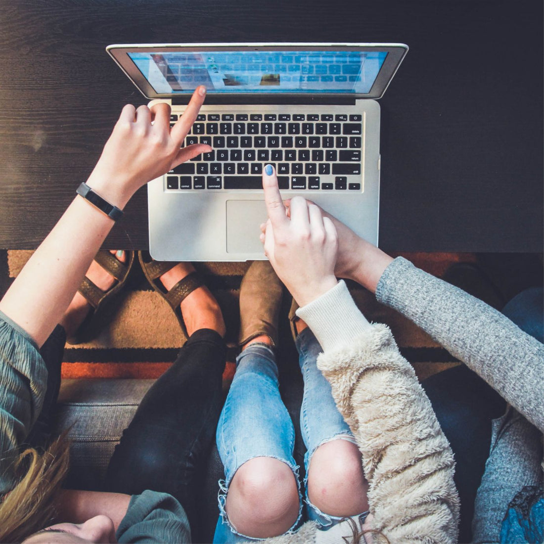 people hovering over a laptop