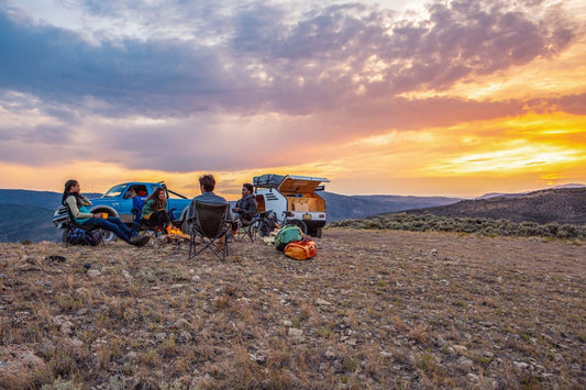 four friends around the campfire at sunset