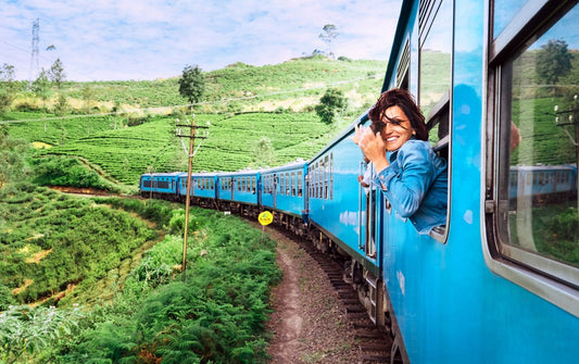 Happy smiling woman looks out from window traveling by train on most picturesque train road in Sri Lanka
