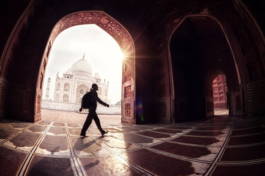 Tourist with backpack walking in the mosque arch near Taj Mahal in Agra