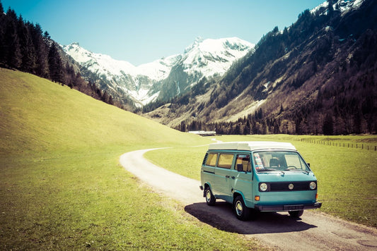 Vintage blue and white VW Bully camping car driving on mountain valley road in Trettachtal valley