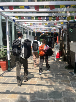 Three people walk through a pergola carrying Eagle Creek duffle bags