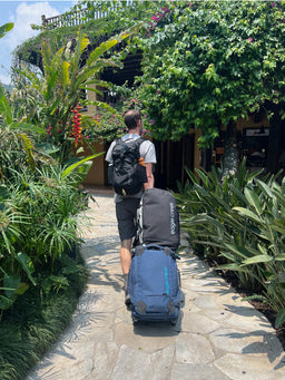 Person walking on a path towing Eagle Creek luggage and a duffel bag