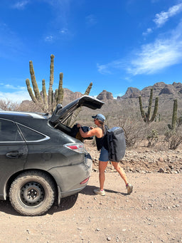 Person loading Eagle Creek duffle bags into a car in the desert