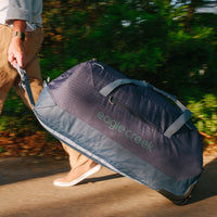 A person rolling a large navy blue duffle bag with wheels