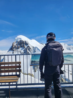 A person wearing an Eagle Creek backpack looking at snowy mountains