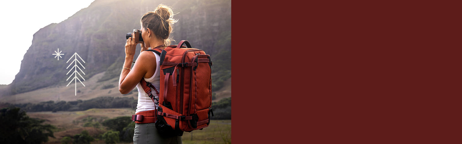 A woman takes photos in Hawaii wearing an Eagle Creek luggage bag