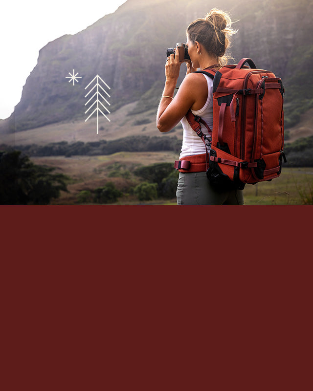 A woman takes photos in Hawaii wearing an Eagle Creek luggage bag