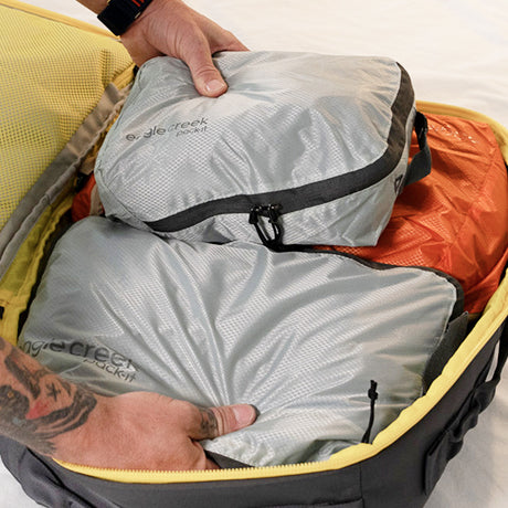 A man packs a travel backpack using packing cubes