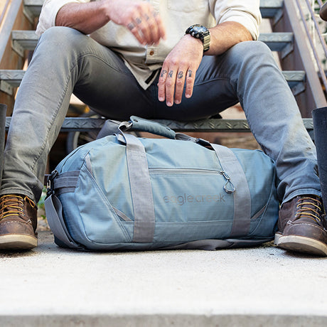 A man sits with a loaded duffel bag