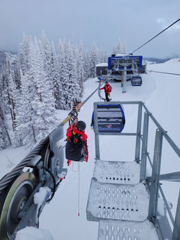 A ski patroller hangs from a cable wearing an Eagle Creek duffle bag