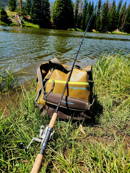 Eagle Creek fishing bag with fishing rod on a grassy bank by a lake
