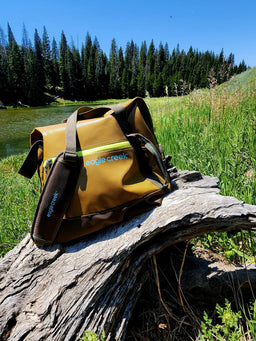 Yellow Eagle Creek tote bag on a log by a lake and forest