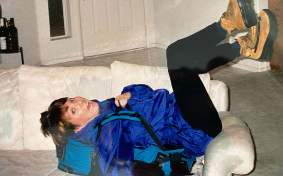 A woman laying on a couch wearing an Eagle Creek travel backpack