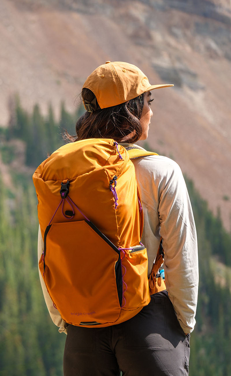 A person smiles while holding a stack of orange and white packing cubes.