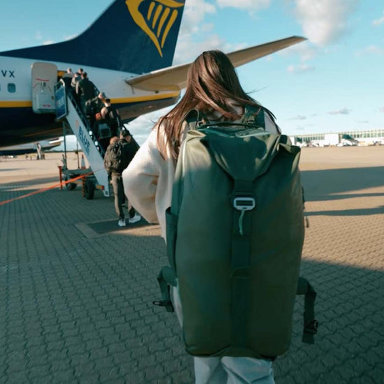 A woman gets ready to board a plane wearing an Eagle Creek travel backpack