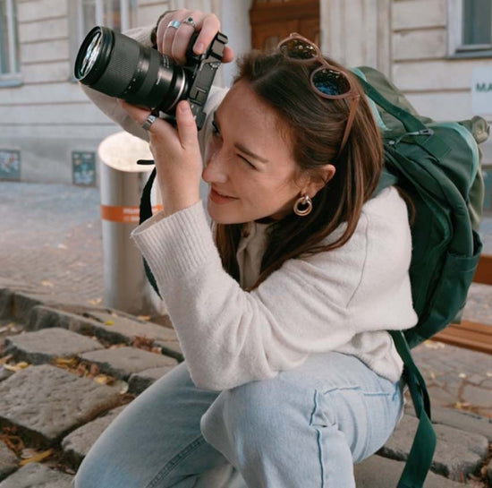 A woman snaps a picture while wearing an Eagle Creek travel backpack