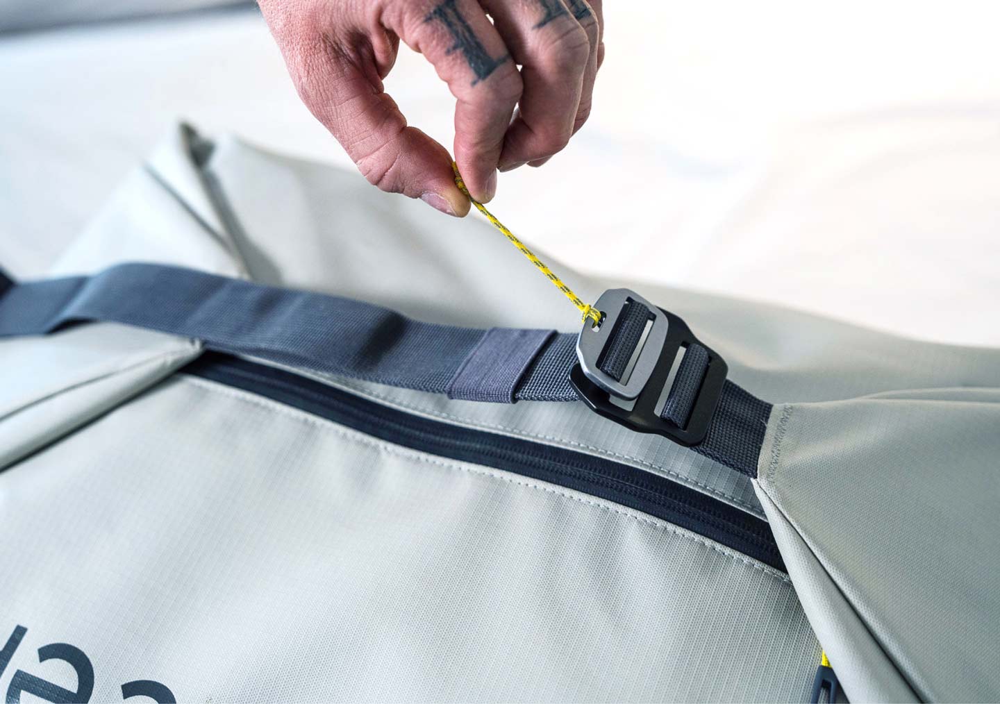 A person fastening the strap closure on a travel backpack