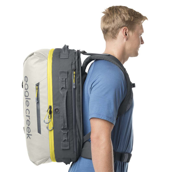 A man wearing an Eagle Creek Tour Travel Pack Storm Grey