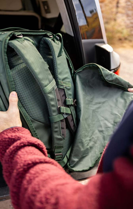 A person zipping away the hidden backpack straps cover on an Eagle Creek travel backpack