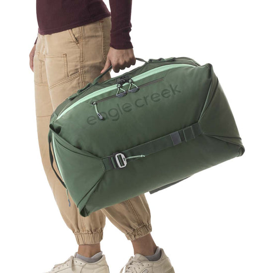 A woman holding a green Tour Travel Backpack