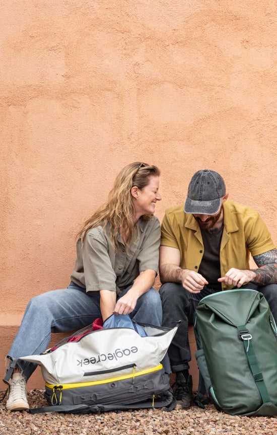 Two people unpacking their travel backpacks