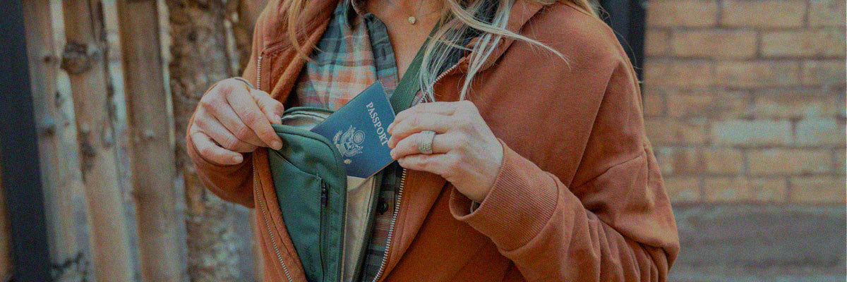 A woman secures her passport in the pocket of an Eagle Creek crossbody bag